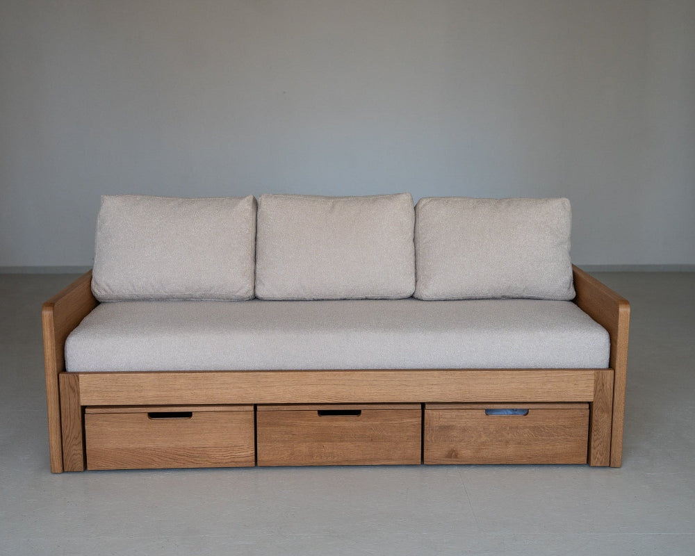 Wooden sofa bed with beige cushions against a plain wall.