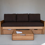 Wooden sofa with storage drawers and a matching coffee table in a minimalistic setting.