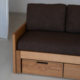 Brown sofa with wooden frame and drawers against a plain wall.
