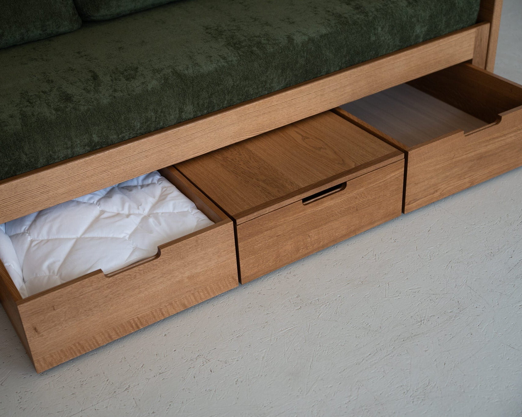 Wooden bed with storage drawers and green cushioned top.