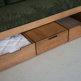 Wooden bed with storage drawers and green cushioned top.