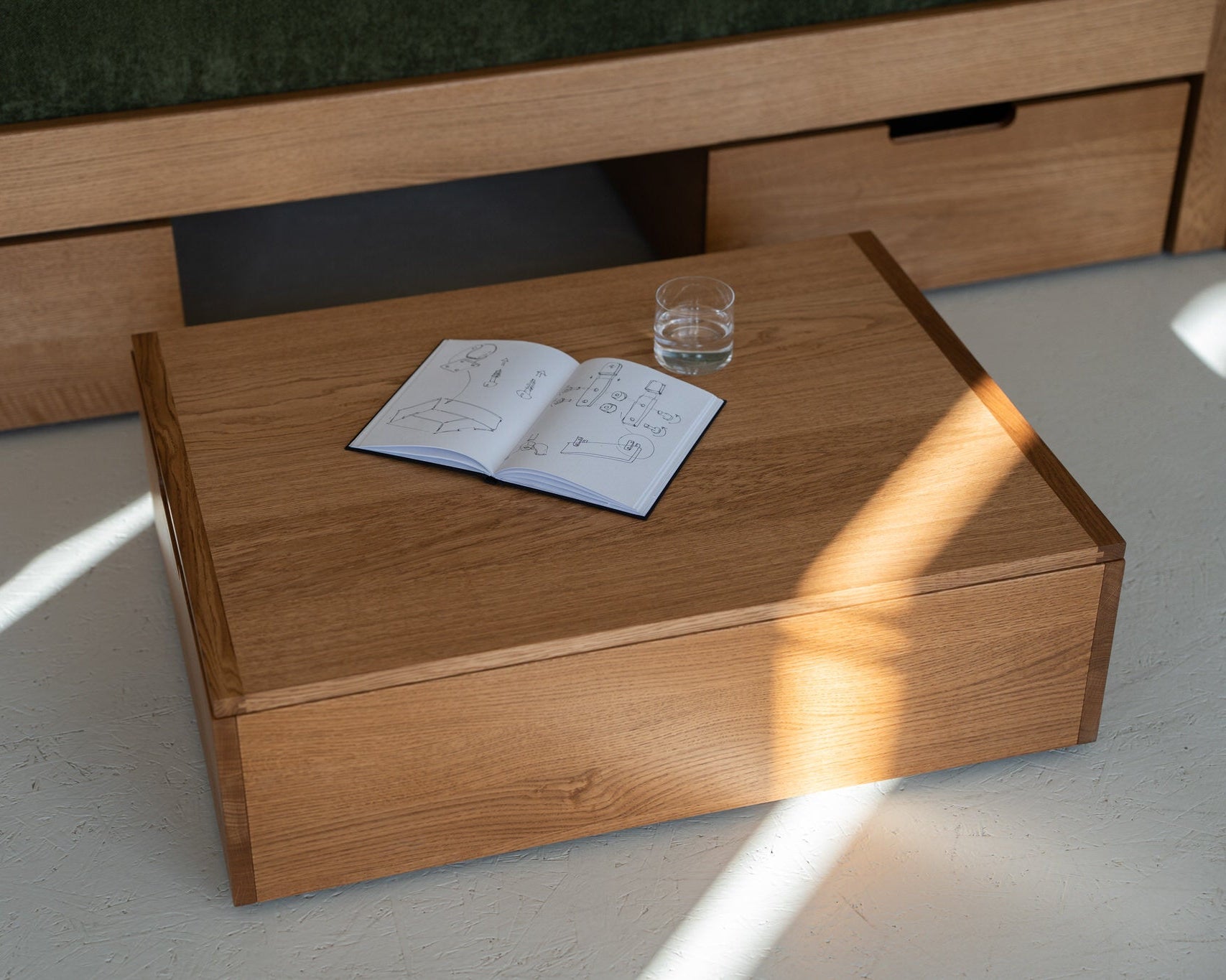 Wooden coffee table with an open book and a glass on a light-colored floor.
