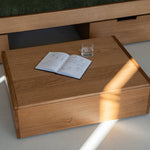Wooden coffee table with an open book and a glass on a light-colored floor.