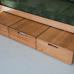 Wooden sofa bed with storage drawers on a gray floor.